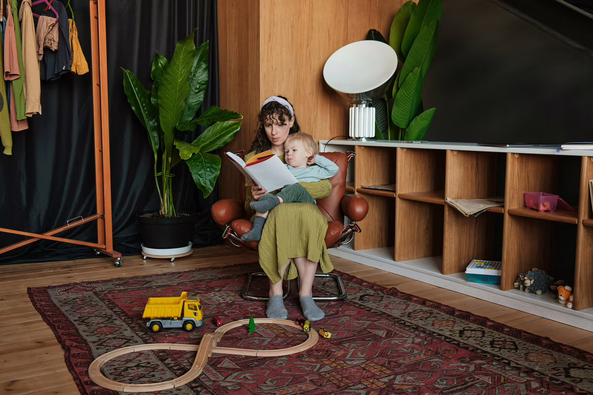 Un parent lit une histoire avec son enfant dans leur salon